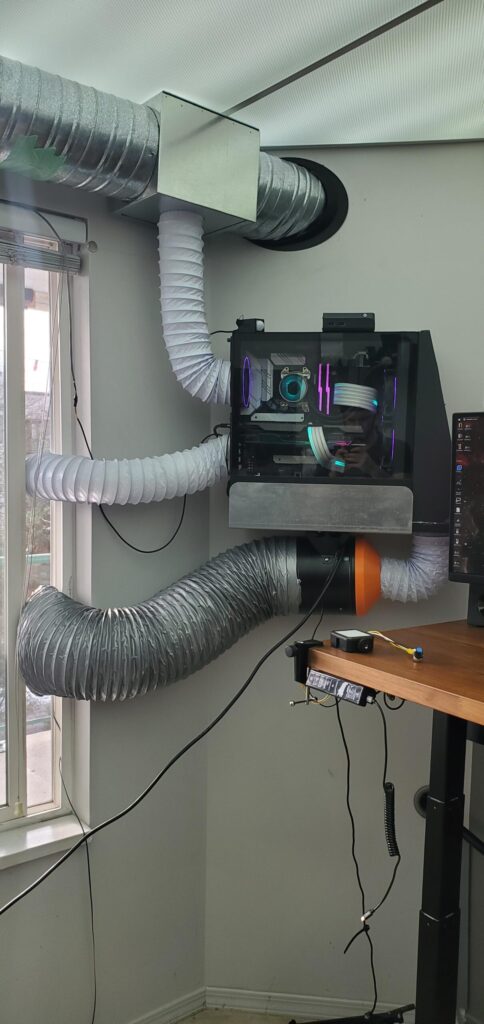 A gaming computer mounted on a wall with flexible air conditioning ducts attached for ventilation and cooling.